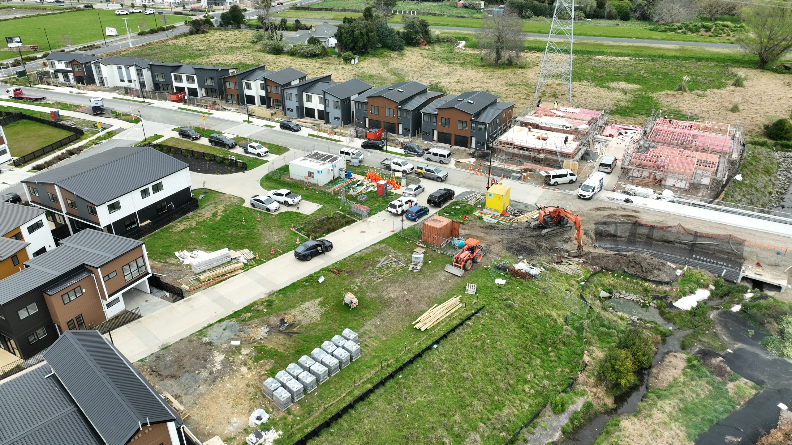 Aerial view of homes, framing and earthworks beside the watercourse